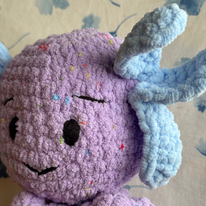 Closeup of purple creature with blue accents on a floral-patterned surface.